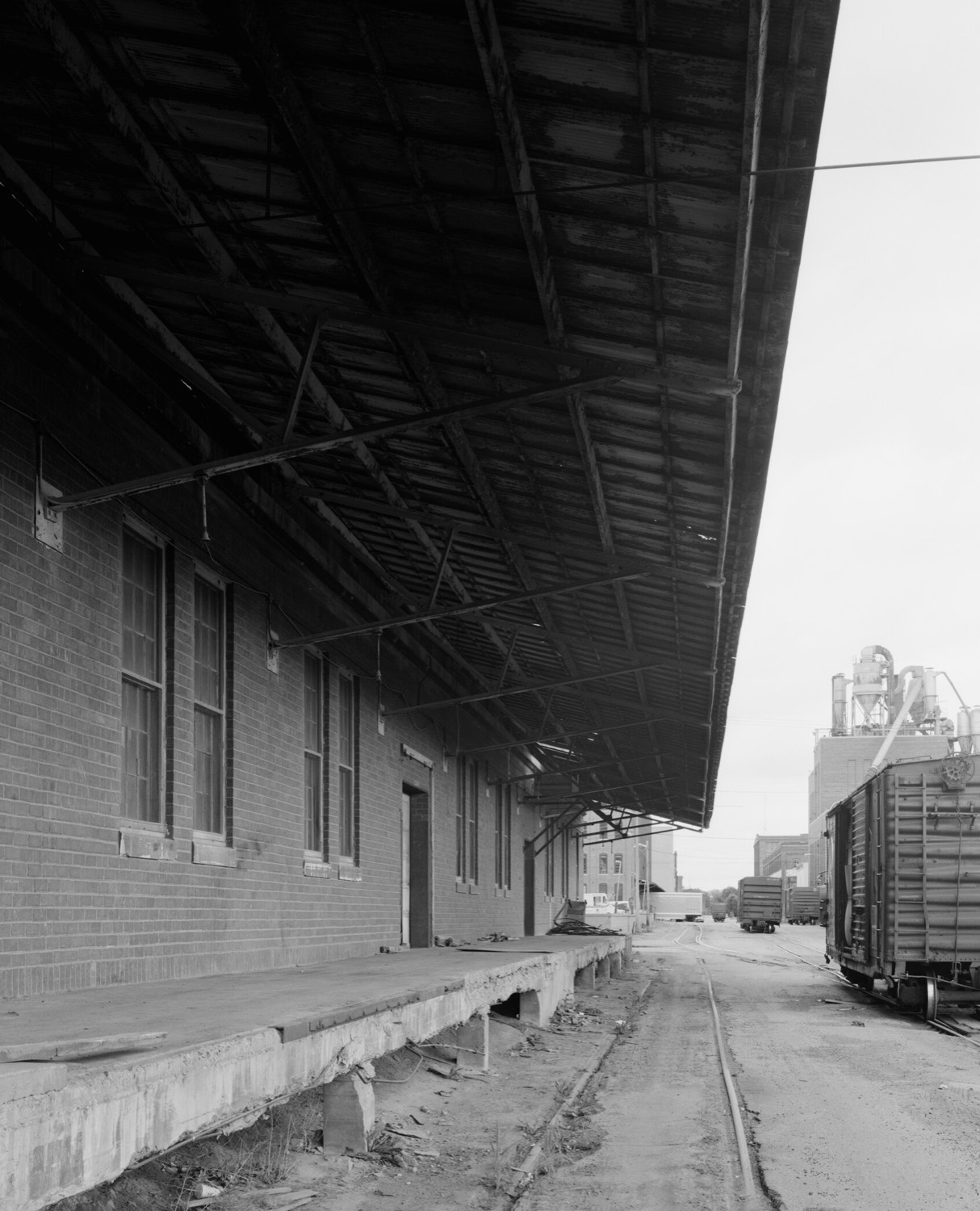 A covered brick loading dock beside a rail siding